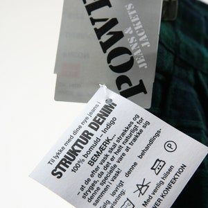 May include: A white tag with black text that reads "Til lykke med dine nye jeans i 100% bomuld - Indigo STRUKTUR DENIM BEM&AElig;RK... - at de efter vask skal str&aelig;kkes og stryges, da det er helt naturligt for denne specielle vare at tr&aelig;kke sig sammen i vask! F&oslash;lg i&oslash;vrigt denne behandlings- anvisning: 40&deg;C Med venlig hilsen POWER KONFEKTION".