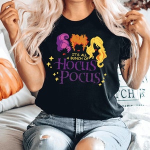 May include: A black t-shirt with a graphic of the Sanderson sisters from the movie Hocus Pocus. The text on the shirt reads "It's all a bunch of Hocus Pocus".