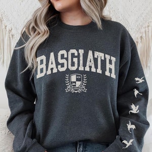May include: A dark gray sweatshirt with the text "BASGIATH" in white, a crest with the text "WAR COLLEGE" and a dragon design on the sleeves.