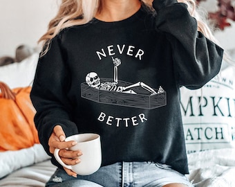 May include: Black sweatshirt with a white graphic of a skeleton in a coffin with the text "Never Better".