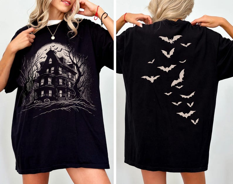 May include: Black t-shirt with a haunted house graphic on the front and a bat design on the back. The front design shows a spooky house with a full moon and bare trees. The back of the shirt has a descending pattern of bats.
