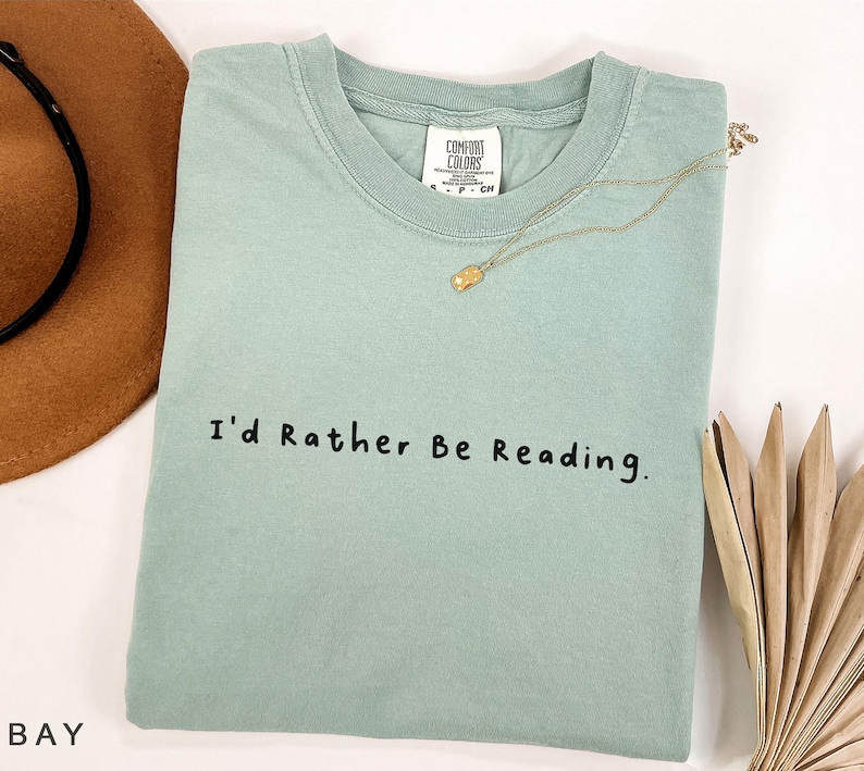 May include: A light green t-shirt with the text "I'd Rather Be Reading." printed in black.