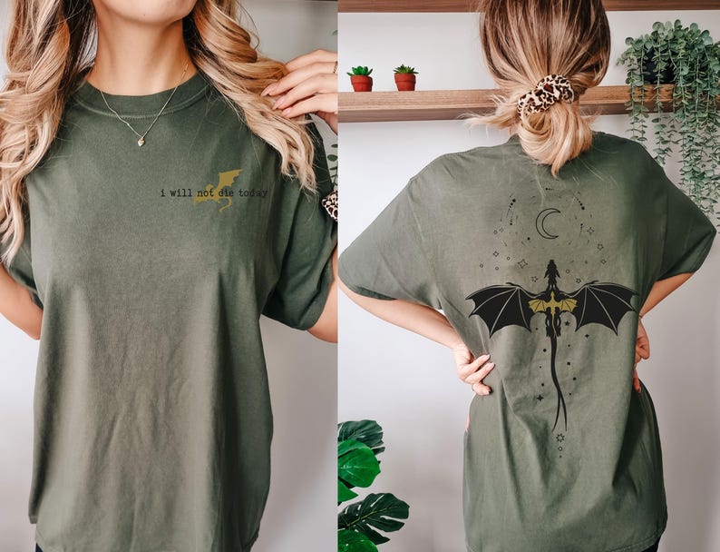 Puede incluir: Una camiseta verde con el texto "I will not die today" en la parte delantera y un drag&oacute;n negro y dorado con una luna creciente en la parte trasera.