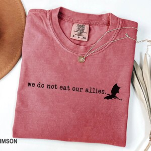 May include: Crimson red t-shirt with a black dragon silhouette and the text "we do not eat our allies."