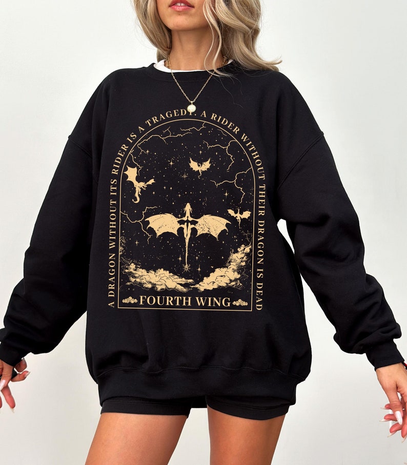 Pode incluir: Camisola de moletom preta com um gr&aacute;fico dourado de um drag&atilde;o e o texto "A dragon without its rider is a tragedy. A rider without their dragon is dead. Fourth Wing."