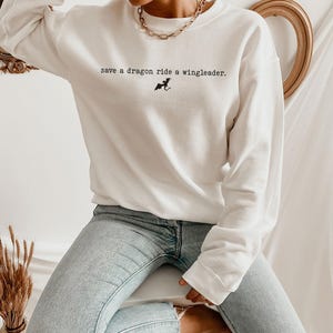 May include: White long-sleeve sweatshirt with the text "save a dragon ride a wingleader." and a small black dragon graphic.