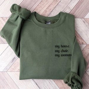 May include: A green sweatshirt with the text "my house. my chair. my woman" printed on the front.
