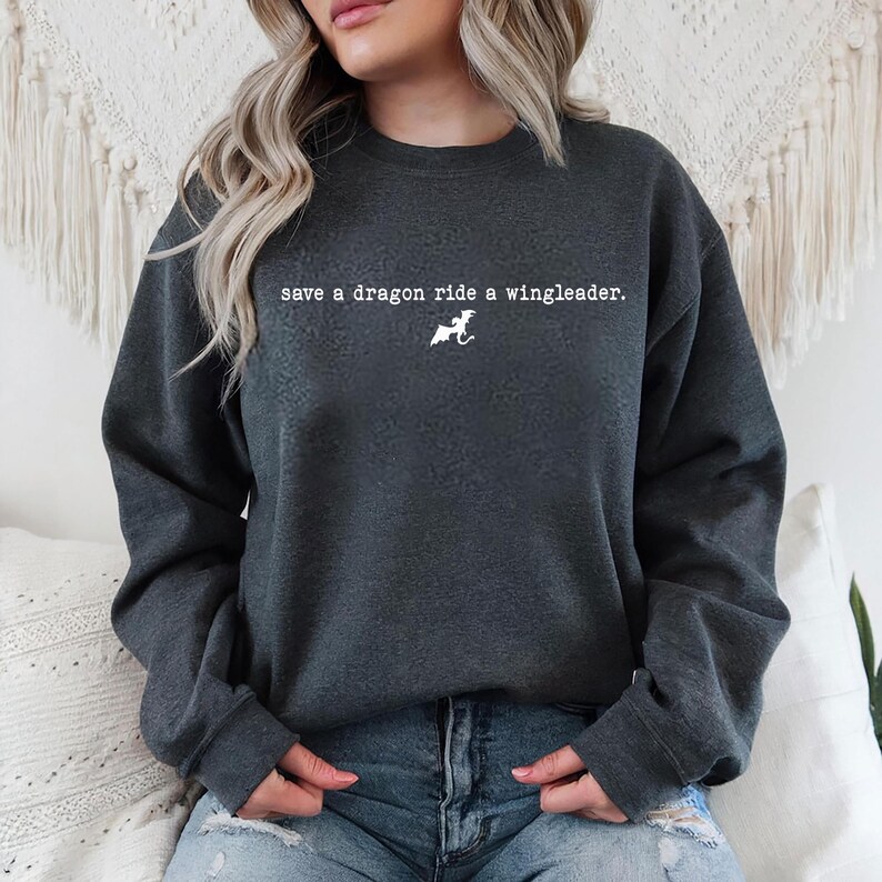 May include: A dark gray sweatshirt with the text "save a dragon ride a wingleader." printed in white. A white silhouette of a dragon is also printed on the sweatshirt.
