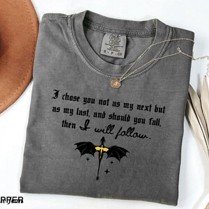 May include: A gray Comfort Colors t-shirt with the text "I chose you not as my next but as my last, and should you fall, then I will follow." A dragon graphic is below the text. A gold necklace is on the shirt.