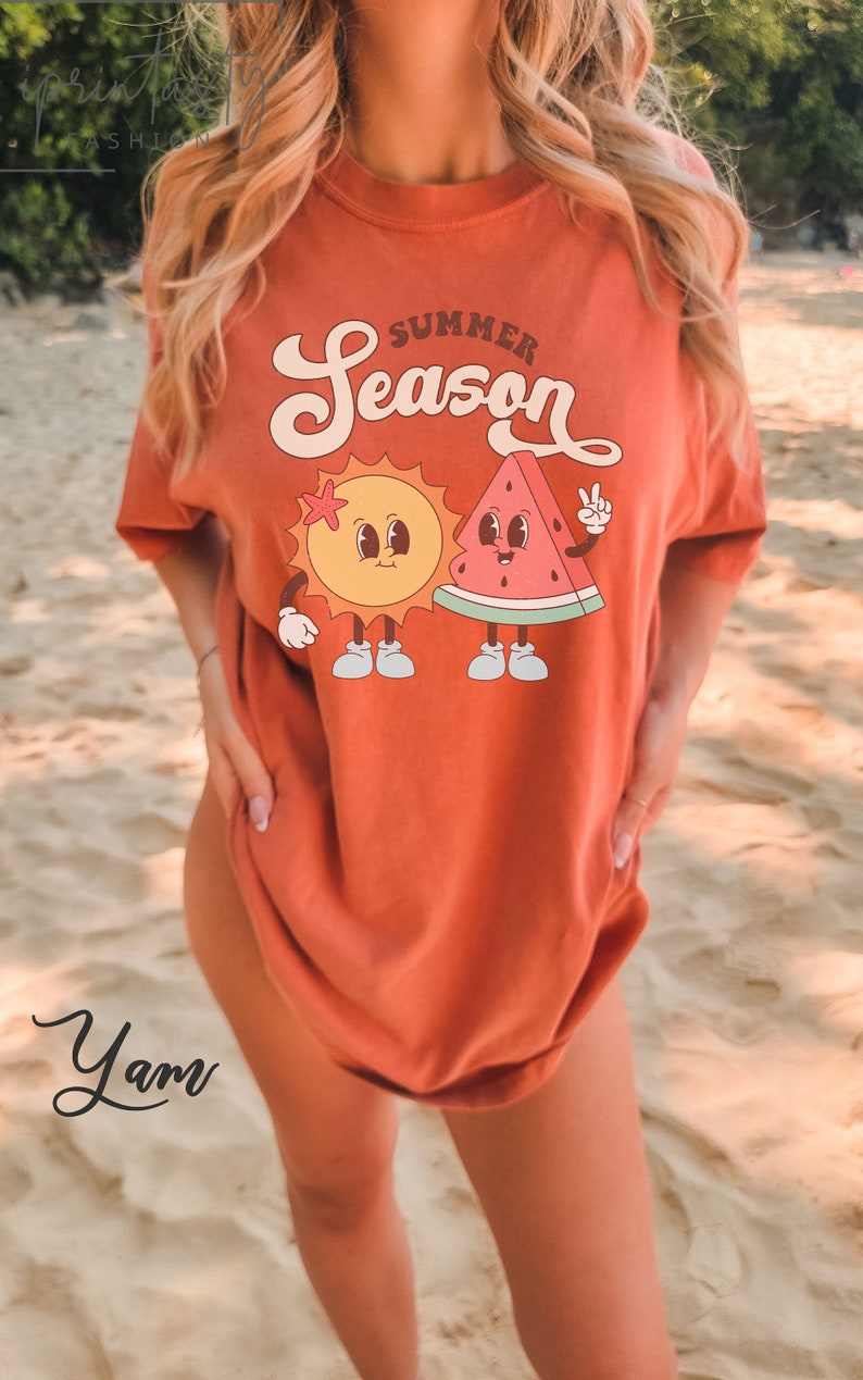 May include: A woman wearing a burnt orange t-shirt with a graphic of a smiling sun and watermelon with the text "Summer Season".