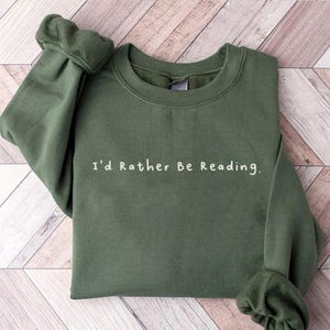 K&ouml;nnte beinhalten: Ein gr&uuml;ner Pullover mit dem Aufdruck "I'd Rather Be Reading." in wei&szlig;.