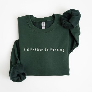 K&ouml;nnte beinhalten: Ein dunkelgr&uuml;ner Pullover mit dem Text "I'd Rather Be Reading." in Wei&szlig;.