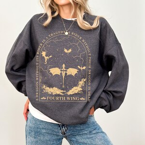 Pode incluir: Uma camisa de moletom cinza escura com uma estampa gr&aacute;fica de um drag&atilde;o e o texto "A dragon without its rider is a tragedy. A rider without their dragon is dead. Fourth Wing."