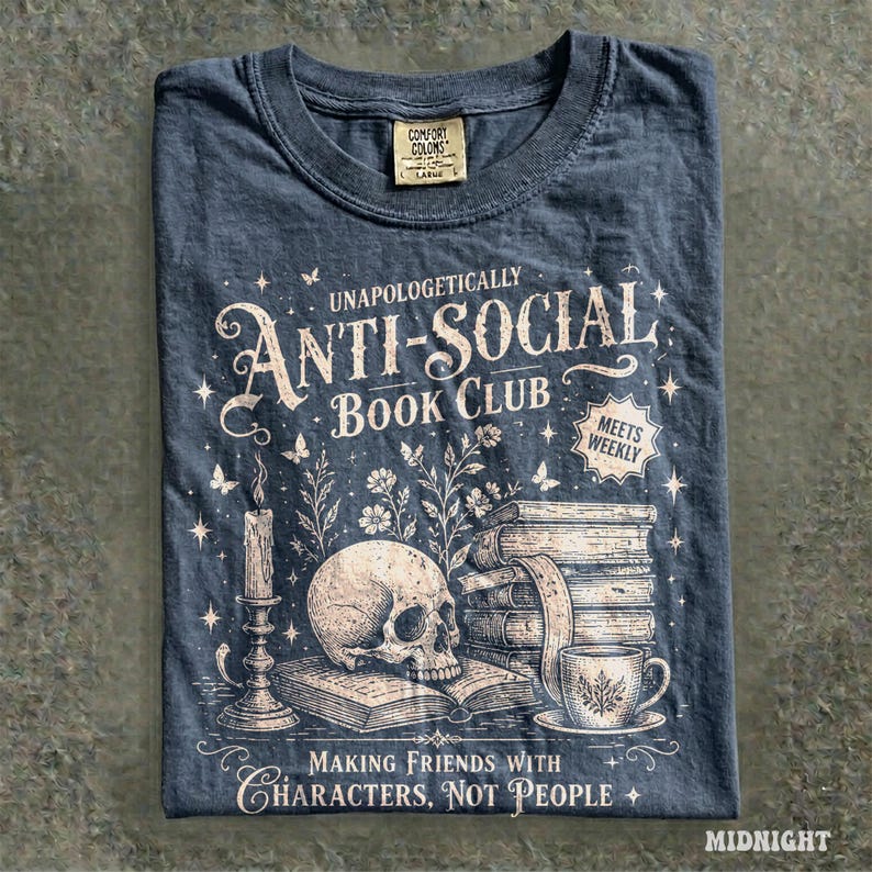 May include: Midnight blue t-shirt with the text "Unapologetically Anti-Social Book Club" and illustrations of a skull, books, a candle, and a teacup. The shirt also has the text "Making Friends With Characters, Not People."