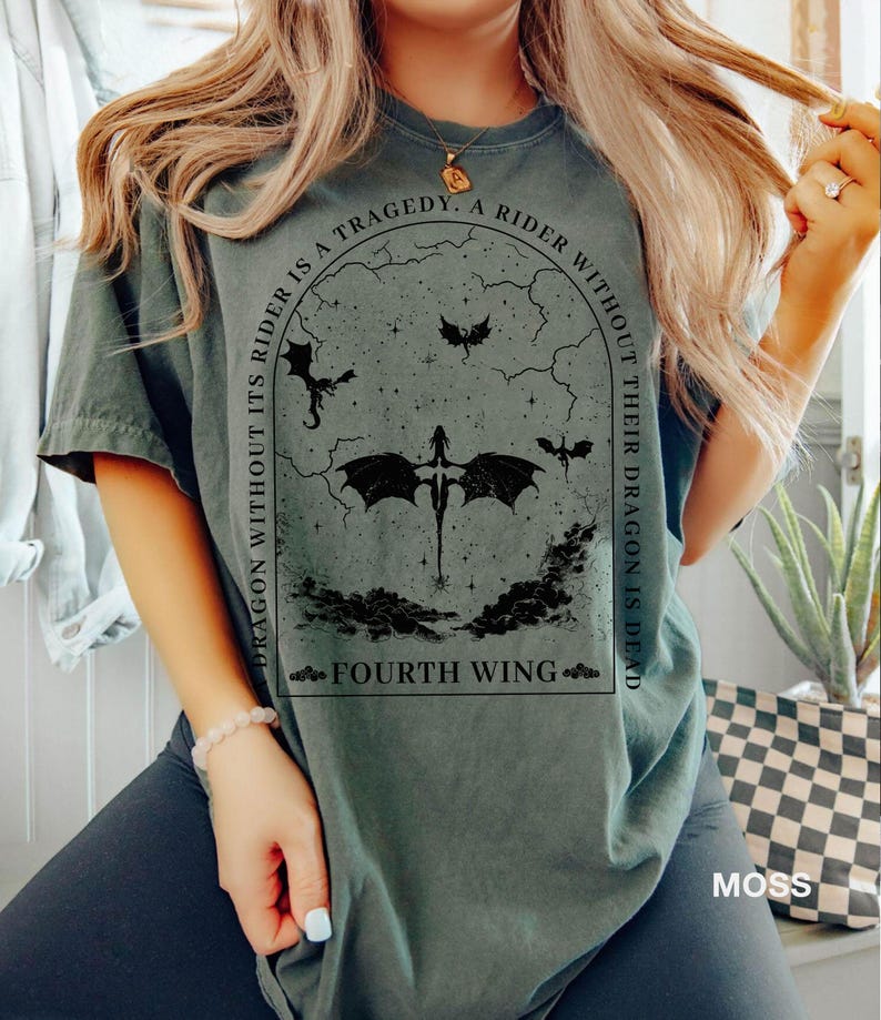May include: A dark green t-shirt with a black graphic print of a dragon and the text "A rider without its dragon is a tragedy. A rider without their dragon is dead. Fourth Wing."