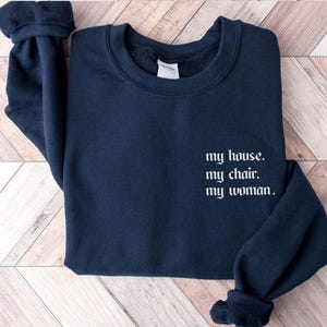 May include: A dark blue sweatshirt with the text "my house. my chair. my woman." printed in white on the front.