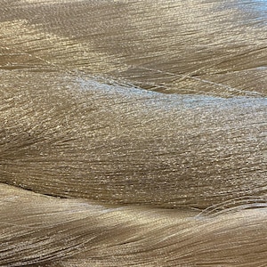 May include: Close-up of shimmering, metallic silver yarn. The yarn is tightly spun, with a slightly textured appearance. The strands are arranged in undulating waves, creating a sense of depth and movement. Ideal for crafting projects.