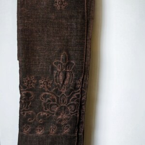 May include: A brown sheer scarf with embroidered floral designs in a lighter brown color.