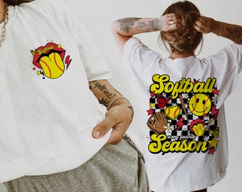May include: Two white t-shirts with a softball theme. The front shirt has a red and yellow softball with the word "Softball" above it. The back shirt has a checkered background with a softball, a bat, a glove, and the text "Softball is my favorite season".