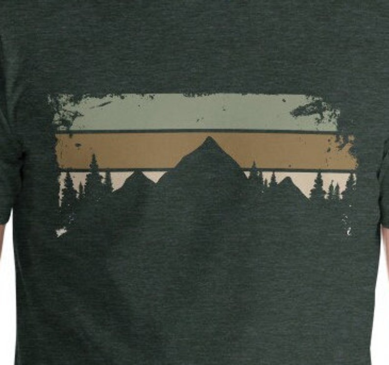 May include: A dark green t-shirt featuring a vintage-style graphic of a mountain range with a sunset behind it. The graphic has a faded, distressed look.