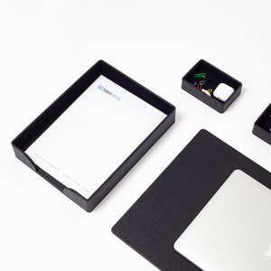 May include: Black desk organizer set with a letter tray, a small tray with paper clips, and a black leather desk mat with a laptop on top. The letter tray has the text "TURBOIT OFFICE" printed on it.