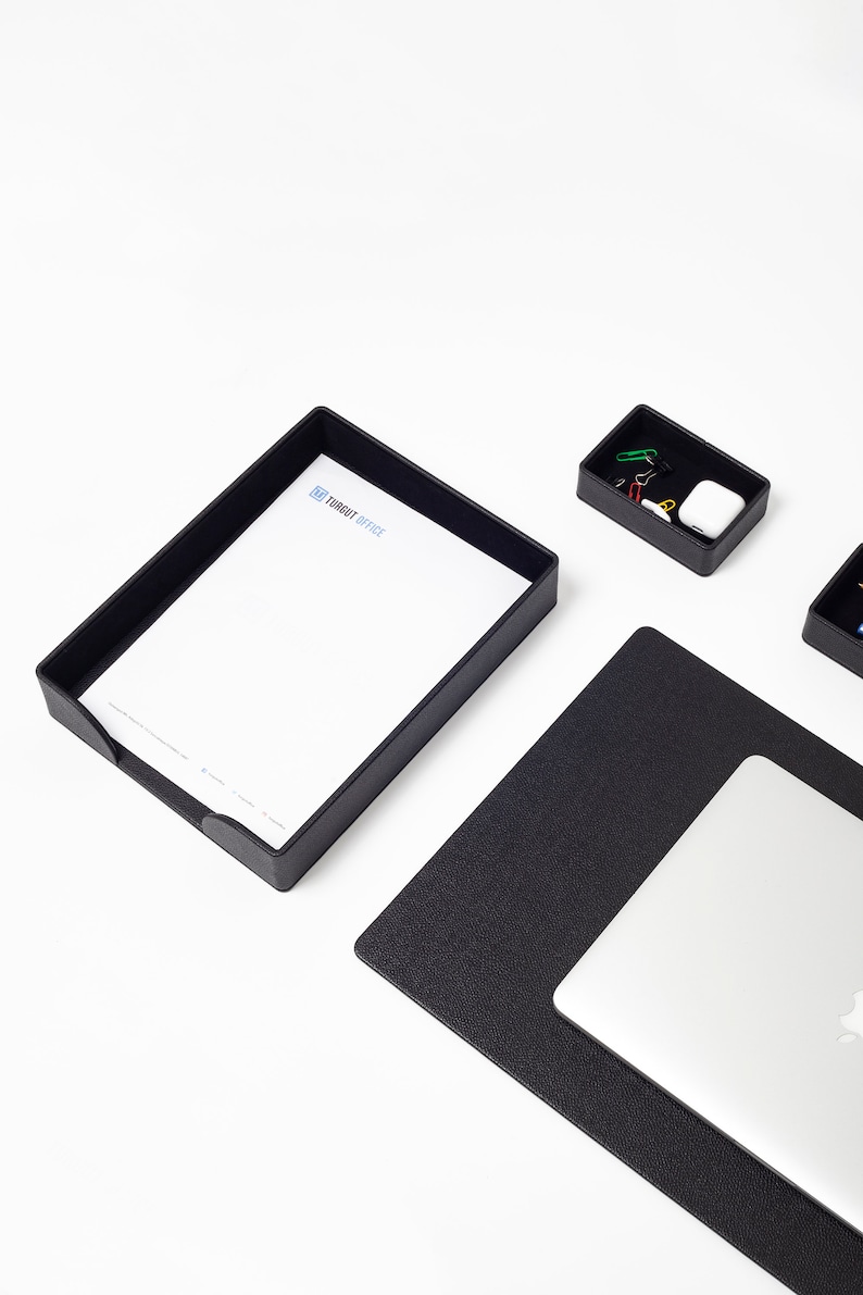 May include: Black desk organizer set with a letter tray, a small tray with paper clips, and a black leather desk mat with a laptop on top. The letter tray has the text "TURBOIT OFFICE" printed on it.