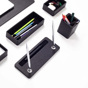 May include: Black leather desk organizer set with a pen holder, pencil holder, and a tray for paper clips.