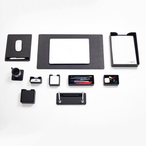 May include: A black desk organizer set with a laptop mat, a pen holder, a pencil holder, a small tray, a mouse pad, and a letter tray.