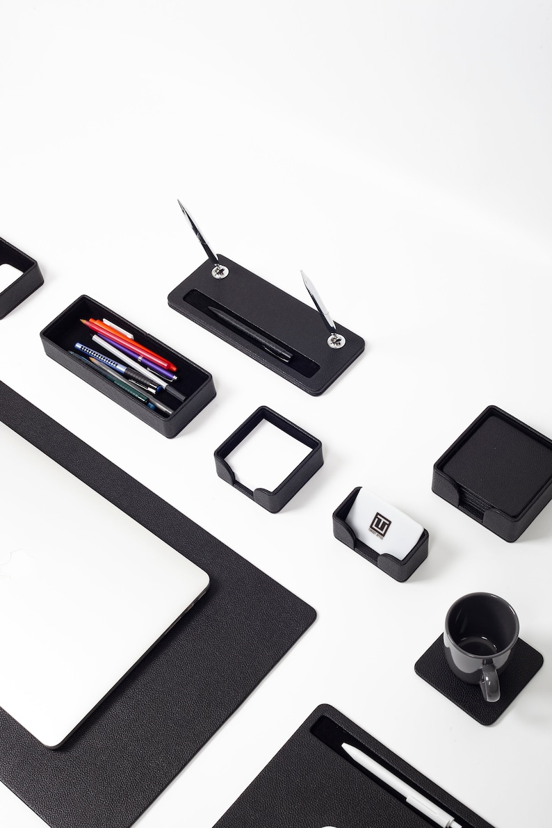 May include: Black leather desk organizer set with a pen holder, business card holder, note pad holder, and a cup holder. The set also includes a black leather desk mat.