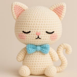 Può includere: Bambola a forma di gatto all'uncinetto fatta a mano, color crema, con papillon azzurro. Il gatto ha gli occhi chiusi, guance rosa e interno orecchie rosa. Il gatto è seduto con la coda arricciata.