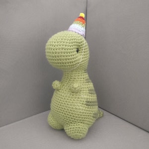 Birthday Timothy the T-Rex with a festive, removable party hat. Party crochet amigurumi stuffed animal dino, celebration dinosaur plush doll
