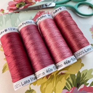 May include: Four spools of Sulky 12wt cotton thread in a dusty rose color. The spools are labeled "100% Long Staple Cotton 46m/50m".