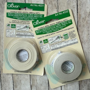 May include: Two packages of Clover fusible web tape for fabric crafts. One package is 5mm wide, the other is 10mm wide. The packaging includes instructions for use and the Clover logo.
