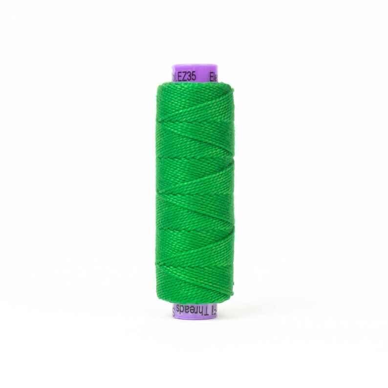 Puede incluir: Una bobina de hilo verde brillante con una etiqueta morada que dice "EZ35" y "Threads".