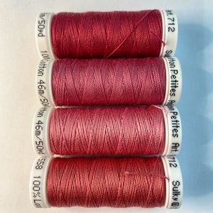 May include: Four spools of red cotton thread, each labeled "Sulky Petites Art. 712" and "100% Cotton 46m/50yd 558 100% Lon/50yd".