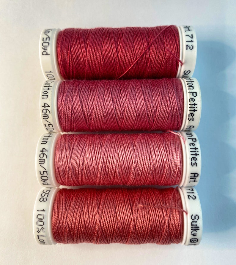 May include: Four spools of red cotton thread, each labeled "Sulky Petites Art. 712" and "100% Cotton 46m/50yd 558 100% Lon/50yd".