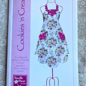 May include: A sewing pattern for a white and pink floral apron with scalloped edges. The pattern is called "Cookies 'n Cream" and is a version of Vanilla House's signature Four Corners Apron.