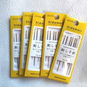 May include: Five packages of sashiko needles, each in a yellow and white package. The packages have Japanese text and the brand name "hidamari" and "LECIEN". The needles are gold-colored and are for sashiko stitching.