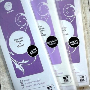 Op de afbeelding: Drie verpakkingen opstrijkbare tussenvoering in lichte, medium en zware gewichten. De paars-witte verpakking bevat tekst zoals Great for Dresses & Blouses, Medium Weight, Heavy Weight, Sewable, Machine Washable en Non-Woven Poly Blend.