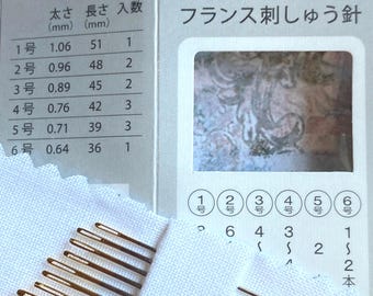May include: A set of 18 gold-toned embroidery needles in a white plastic case. The needles are arranged in rows by size, with the largest needles at the top and the smallest needles at the bottom. The case also includes a small card with the needle sizes and lengths in millimetres. The card also includes the text "No. 4302" and "French Embroidery Needles".