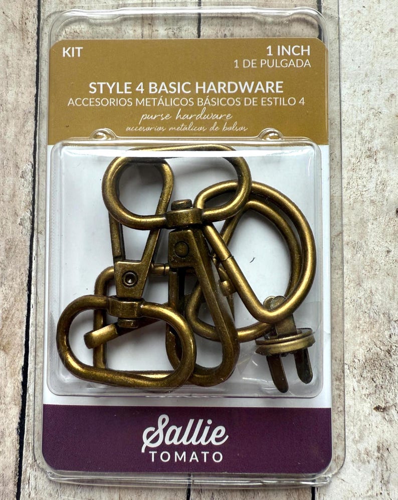 May include: A Sallie Tomato Style 4 Basic Hardware kit containing antique brass-coloured metal swivel lobster clasps and D-rings for purses. The packaging is labelled 1 inch and includes multiple pieces of hardware sealed in a clear plastic blister pack.