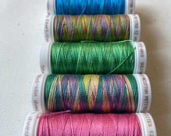 May include: Five spools of embroidery thread in various colors, including blue, green, yellow, pink, and purple. The spools are labeled "Sulky Cotton Petites 12 wt.  Art. 12-4018" and "Sulky Cotton Petites 12 wt. Art. 12-4018".
