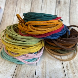 May include: A stack of colorful leather cords in various shades of green, yellow, red, blue, brown, and pink. The cords are arranged in a circular pattern, with the ends of each cord overlapping.