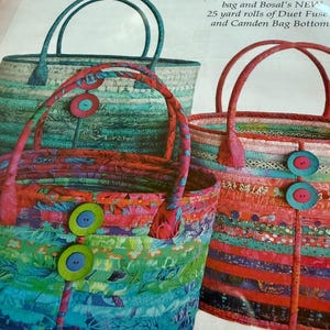 May include: A sewing pattern for Camden Bags featuring three fabric tote bags with horizontal striped patterns in blue, green, and red tones. Each bag has two handles and two large circular buttons. Text includes dimensions for large, medium, and small sizes.