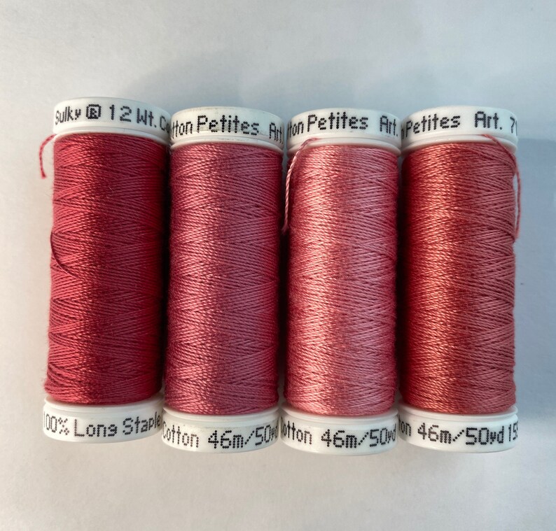May include: Four spools of Sulky 12 Wt. Cotton Petites thread in a dusty rose color. Each spool is labeled "100% Long Staple Cotton 46m/50yd".