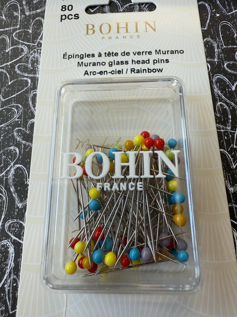 Peut inclure: Un r&eacute;cipient en plastique transparent rempli de 80 &eacute;pingles &agrave; t&ecirc;te de verre color&eacute;es. Les &eacute;pingles sont argent&eacute;es avec des t&ecirc;tes de verre arc-en-ciel. Le r&eacute;cipient est &eacute;tiquet&eacute; "BOHIN FRANCE" et "&Eacute;pingles &agrave; t&ecirc;te de verre Murano".