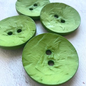 May include: Four green buttons with a textured surface and two holes each.