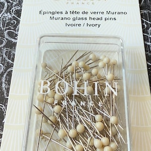 Peut inclure: Un r&eacute;cipient en plastique transparent rempli de 80 &eacute;pingles &agrave; t&ecirc;te de verre de couleur ivoire. Les &eacute;pingles sont fabriqu&eacute;es par Bohin France. Le r&eacute;cipient est &eacute;tiquet&eacute; "&Eacute;pingles &agrave; t&ecirc;te de verre Murano Murano glass head pins Ivoire / Ivory".