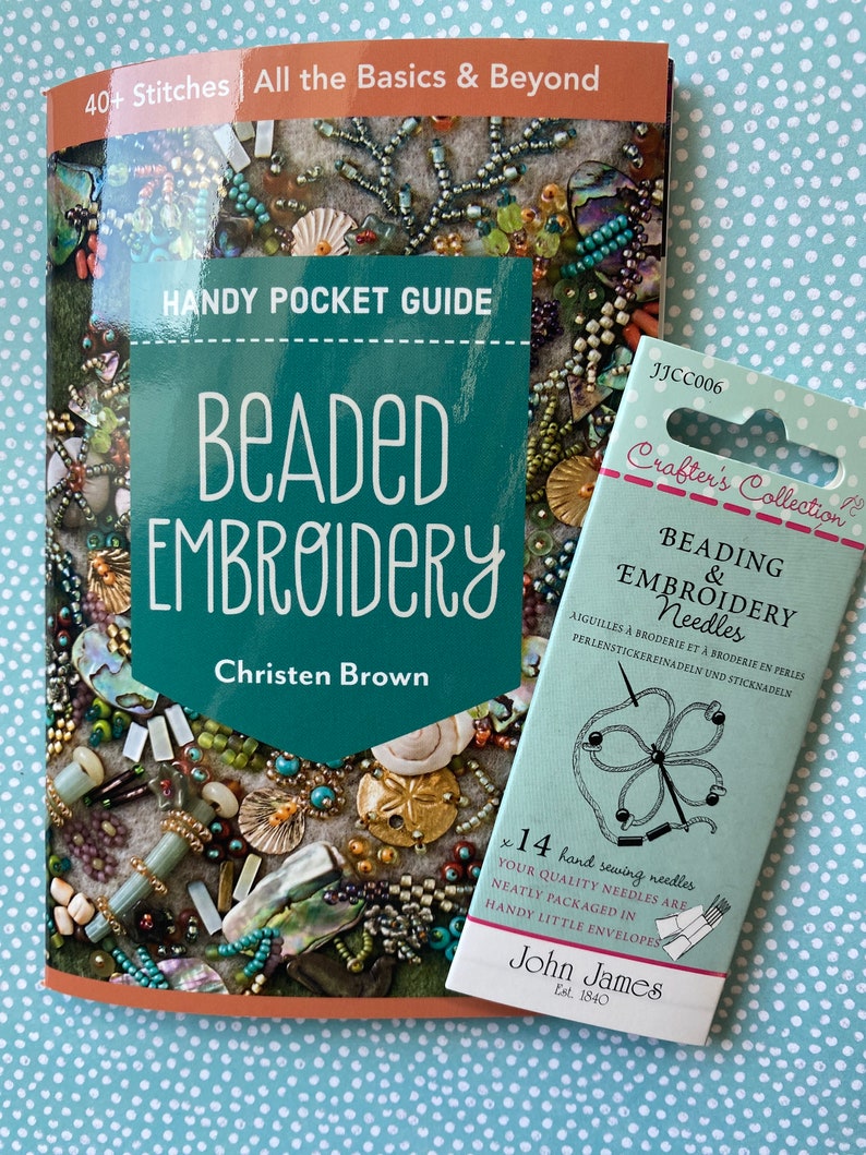 May include: A "Beaded Embroidery" book by Christen Brown, with a teal cover, next to a package of "Beading & Embroidery Needles" by John James. The book cover features a close-up of beaded embroidery. The needle package is light green.
