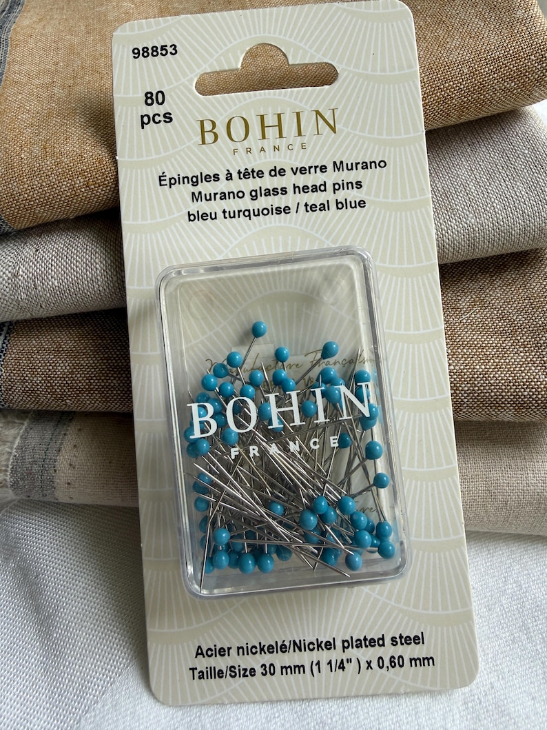 K&ouml;nnte beinhalten: Eine Packung mit 80 Bohin France Murano Glaskopfstecknadeln in T&uuml;rkisblau. Die Stecknadeln bestehen aus vernickeltem Stahl und messen 30 mm mal 0,60 mm. Die Verpackung ist wei&szlig; mit goldenem Text und einem durchsichtigen Kunststoffgeh&auml;use.